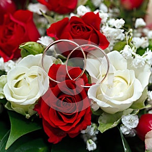 Golden wedding ring on the bride's bouquet. Bouquet of red and w