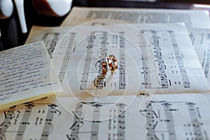 Golden wedding ring on old sheet music, casting a heart shaped shadow.