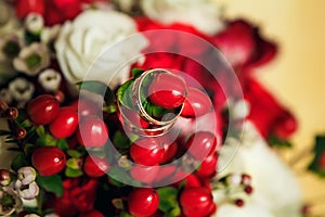 Golden wedding rings on the background of a wedding bouquet of red roses