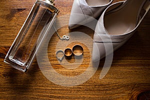 Golden wedding rings, bridal shoes and perfume on brown background. accessories.