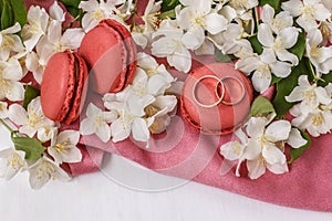 Golden wedding rings with flowers white Jasmine, macaroons and pink drape