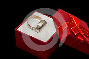 Golden wedding rings in red present box on black background