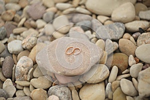 Golden wedding rings on a stones. Rustic wedding concept.