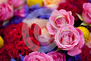 Golden wedding rings on wedding bouquer of pink roses and violet and red flowers