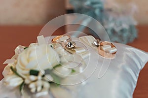 Golden wedding rings on white decorative cushion with flowers