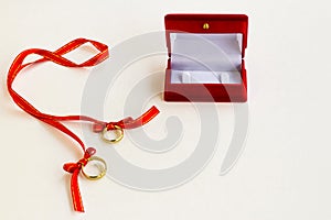 Golden wedding rings on white surface with ring box