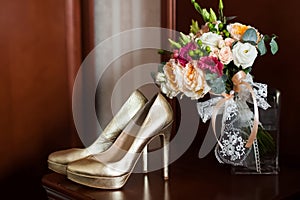 Golden wedding shoes and gentle bridal bouquet with lace bow