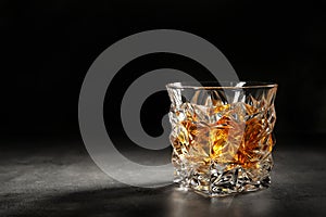 Golden whiskey in glass with ice cubes on table.