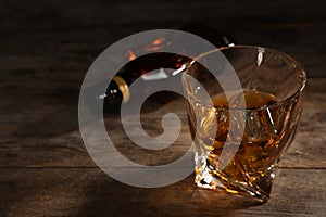 Golden whiskey in glass with ice cubes on table