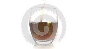 Golden Whiskey Pouring into Glass. Pouring of scotch whiskey or cognac into glasses with ice cubes on white  background