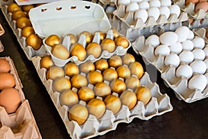 Golden, white, brown eggs in a tray for sale at a farmer\'s market for Easter, success, prosperity concept