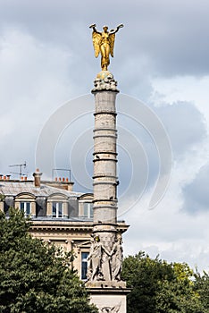 A golden winged statue on the top of a column in the downtown of Paris, France