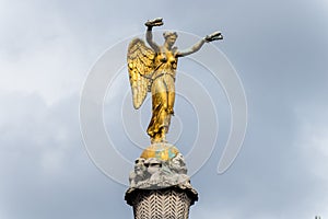 A golden winged statue on the top of a column in the downtown of Paris, France