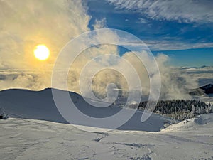 Golden winter morning sun rises above scenic backcountry covered in fresh snow.