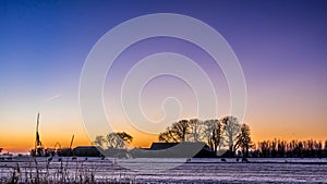 Golden winter sun on snowy paddock behind farmhouse and trees