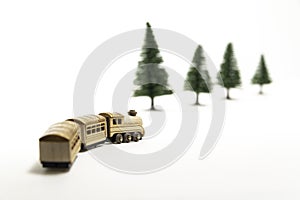 Golden wooden toy train turn right isolated from white background and blur pine tree