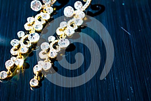 Golden, yellow earrings on the ears. Evening and elegant decorations with large and small white stones.