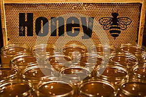 Golden yellow honey in glass jar on wooden board Closeup Copy space with bee logo textspace