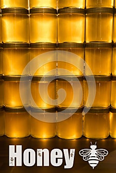 Golden yellow honey in glass jar on wooden board Closeup Copy space with bee logo textspace