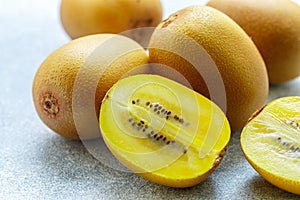 Golden yellow organic kiwi. Whole and cut ripe juicy fruits on grey background. kiwifruit