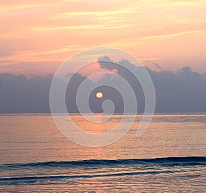 Golden Yellow Sun Rising among Clouds at Horizon with Reflection in Water with Bright Warm Colorful Sky