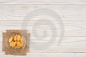 Goldfish cracker in a glass bowl on a white wooden table.