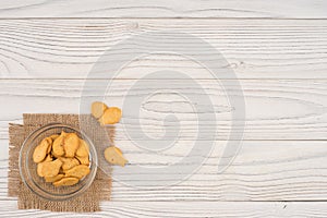 Goldfish cracker in a glass bowl on a white wooden table.