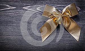Goldish bow on wooden board holiday concept photo