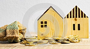 Golds coin in the hemp sack and two houses on the table with copy space