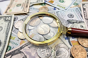 Golen magnifying glass on different dollars money as financial background