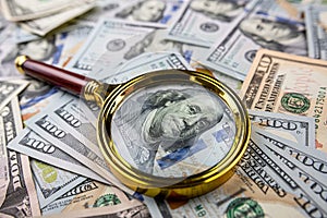 Golen magnifying glass on different dollars money as financial background