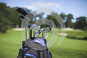 Golf bag and clubs against defocused golf course