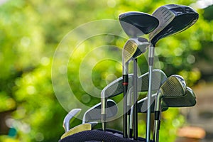 Golf bag and clubs in front of a blurred golf course background