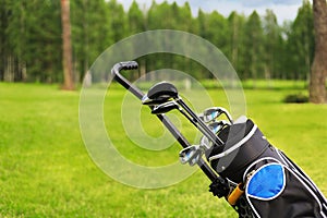 Golf bag and clubs in front of de focused green with sand traps. photo