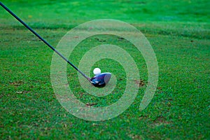 Golf ball behind driver at driving range, plenty of copy-space a