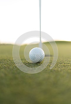 Golf ball close to cup hole on putting green