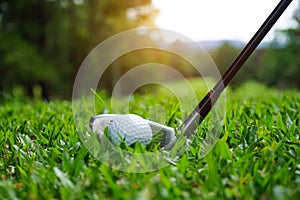 Golf ball and golf club in beautiful golf course at Thailand. Collection of golf equipment resting on green grass with green