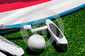 Golf ball and club with flag of Luxembourg on green grass. Golf championship in Luxembourg