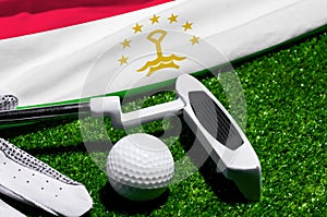 Golf ball and club with flag of Tajikistan on green grass. Golf championship in Tajikistan
