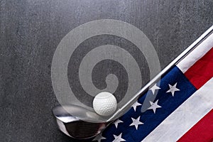 Golf ball and golf club with flag of USA on black table background, sport concept