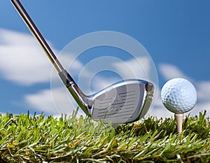 Golf ball and club. Golf club and golf ball about to tee off against a blue sky