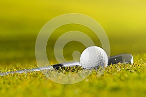 Golf ball and club on grass