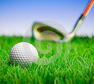 Golf ball with club in grass field