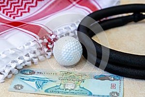 Golf Ball, Dirham Banknote, and Traditional Arab Male Clothes - kaffiyah and agal photo