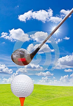 Golf ball and driver on green grass