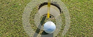 Golf ball on the edge of hole on green closeup