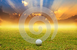 Golf ball in fairway on sunrise background