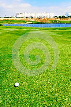 Golf ball on fairway with water hazard in front of green photo