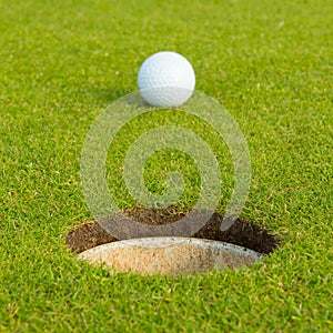 Golf ball in front of the hole, focus on the hole