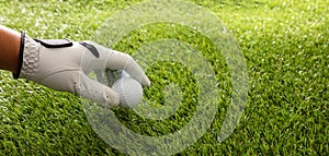 Golf ball in gloved hand, green course lawn background, close up view